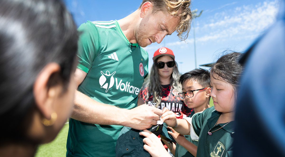 Wanderers captain and Socceroos goalkeeper Lawrence Thomas signing merchandise for students